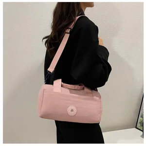 Vue détaillée du sac porté rose cylindrique par le modèle, montrant la sangle et la fermeture.