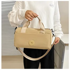 Sac bandoulière cylindrique beige en tissu, vue détaillée du tissu résistant et des poignées.