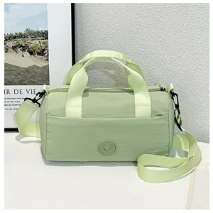 Détail du sac porté épaule vert léger avec poignées et sangle en tissu résistant.