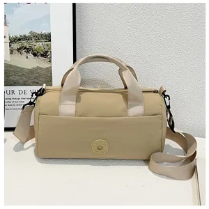 Sac coussin beige minimaliste avec double poignée et bandoulière réglable pour le voyage.