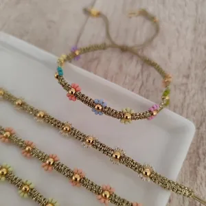 Dettaglio del braccialetto dell'amicizia in perline intrecciate a mano con margherite dorate.