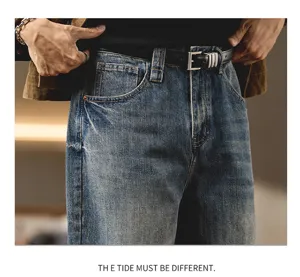Detailed view of men's vintage washed blue loose denim jeans with a stylish black belt.