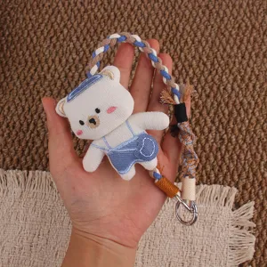 Süßer gestrickter Bär Schlüsselanhänger und geflochtener Handyband Anhänger im Detail.