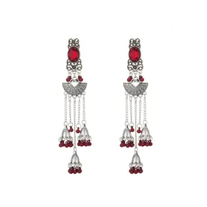 Vista detallada de pendientes étnicos de plata con piedras rojas y dijes de campana.