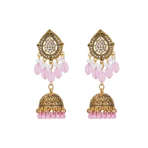 Close-up detail of antique gold drop earrings with pink beads and sparkling crystal stones.
