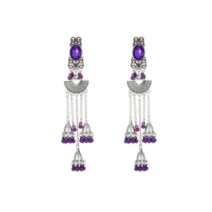 Primer plano de pendientes largos plateados étnicos con piedras moradas y detalles de campana.