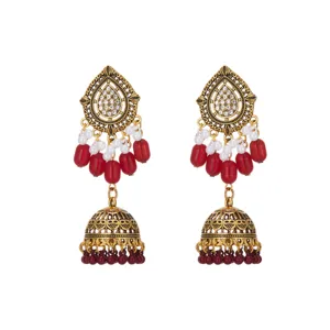 Close-up detail of vintage gold-plated ethnic jhumka earrings with red beads and crystals.