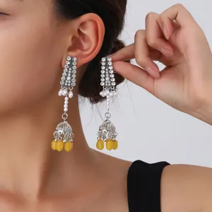 Close up of vintage silver rhinestone pearl and yellow jhumka tassel drop earrings detail.