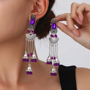 Primer plano detallado de pendientes étnicos de plata vintage con piedras de cristal moradas.