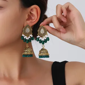 Detailed view of ethnic vintage gold drop jhumka earrings with green beads and pearls.