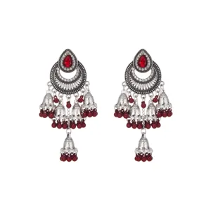 Primer plano detallado de pendientes jhumka de plata étnicos con piedras rojas.