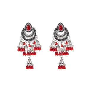 Primer plano detallado de pendientes étnicos de plata antigua con cuentas rojas y piedras.