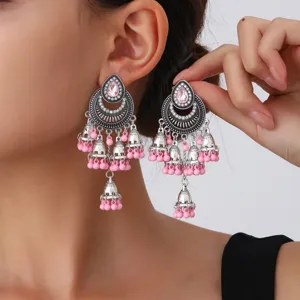 Primer plano detallado de pendientes étnicos vintage color plateado con cuentas rosas.