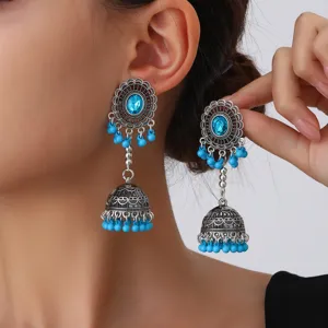 Detalle en primer plano de pendientes bohemios de campana calados con cuentas azules.