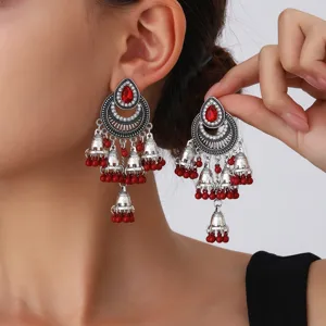 Primer plano detallado de pendientes jhumka de plata vintage con piedras rojas y cuentas.
