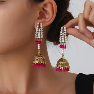 Vue détaillée de boucles d'oreilles jhumka dorées anciennes avec perles roses.