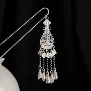 Detalle de horquilla de metal plateado en forma de Pipa con delicado trabajo de borlas.