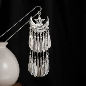 Vista detallada de la horquilla Miao de plata tradicional china con luna, estrella y borlas.