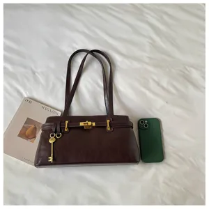 Vue de détail d'un sac à épaule minimaliste marron foncé avec accessoires dorés.