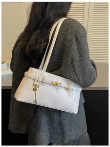 Détails du sac à épaule minimaliste de couleur claire avec serrure en métal et clé.