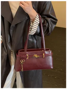 Vue détaillée d'un élégant sac à main en cuir rouge foncé avec serrure et clé dorées.