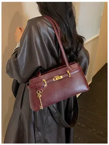Sac épaule élégant en cuir bordeaux pour femme, fermoir métallique classique, design minimaliste.