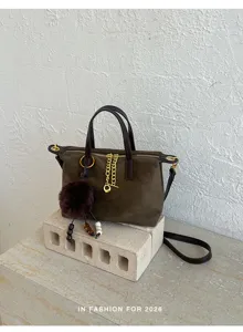 Brown suede crossbody bag detail showing metallic chain decoration and plush pompom charm