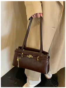 Détail de sac à bandoulière en cuir minimaliste marron foncé avec serrure et clé.
