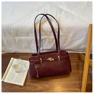 Vue détaillée de l'élégant sac à épaule bordeaux avec serrure dorée et breloque clé.