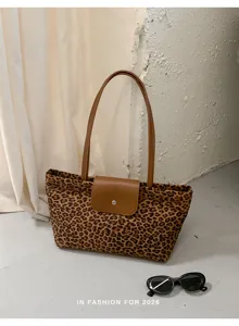 Leopard print tote bag with brown leather handles and front flap closure for daily use.