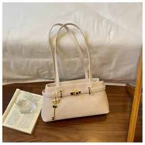 Détail du sac à épaule beige minimaliste, doté de superbes finitions dorées et d'un pendentif.