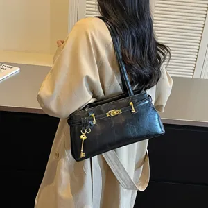 Sac à épaule élégant en cuir unicolore avec accessoires dorés et breloque clé.