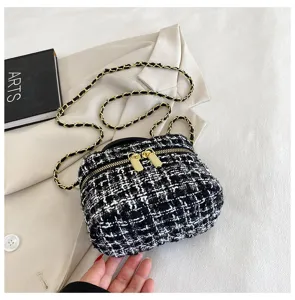 Zwarte en witte tweed mini ketting tas detail, elegante schoudertas met goudkleurige ketting.