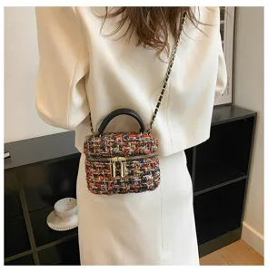 Gedetailleerd shot van een stijlvolle tweed mini crossbody tas met ketting en zwart handvat.