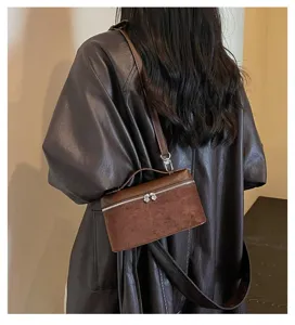 Vista detallada del elegante bolso bandolera de ante marrón con cremallera chic.
