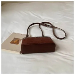 Vista detallada del bolso cruzado marrón estilo vintage con textura de ante y cuero, chic.
