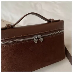 Detalle de bolso caja en ante marrón, elegante necesir con cremallera de corazón y asa.