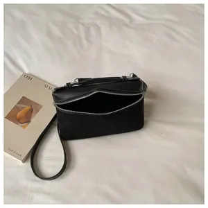 Primer plano detallado de un bolso cruzado negro con paneles geométricos sobre fondo blanco.