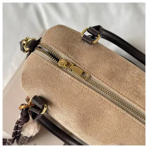 Detailed view of the vintage suede barrel bag, featuring brown leather handles and gold-tone zipper.