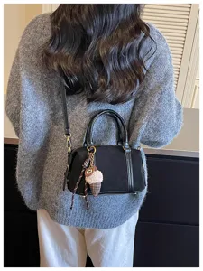 Detail view of a chic black retro crossbody bag, featuring suede texture and a cute charm.