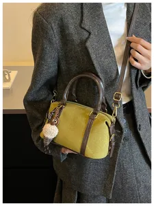 Detailed view of vintage olive green shoulder bag with brown contrast trim and plush charm.