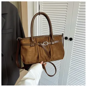 Détail de sac à épaule en daim marron, sac à main vintage de voyage avec boucle et sangle.