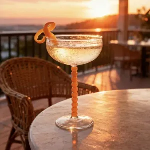 Decorative high-footed cocktail glass with orange beaded stem for home bar or party use.