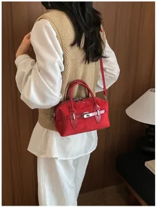 Red suede pillow bag with metal lock detail, chic shoulder strap design for daily commute.
