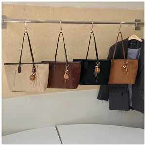 Gedetailleerd overzicht van de dames suède tote tas met textuur, kleuren en houten kralen hanger.