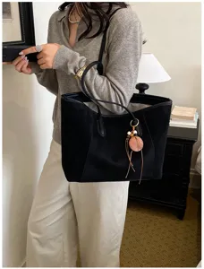 Detailopname van een chique zwarte suède shopper met delicate houten hanger in stijl.