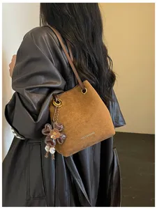 Brown suede retro bucket bag with metal chain and charm detail for women commuter fashion.