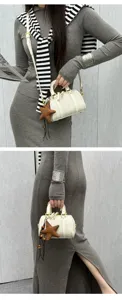 Detailed view of a chic white tweed Boston handbag with gold hardware and a cute star charm.