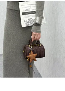 Close-up detail of the brown plaid Boston handbag with star charm, fashion style.