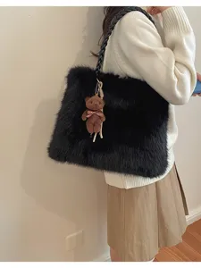 Detalle de bolso tote de felpa negro muestra textura suave y un tierno osito colgante.